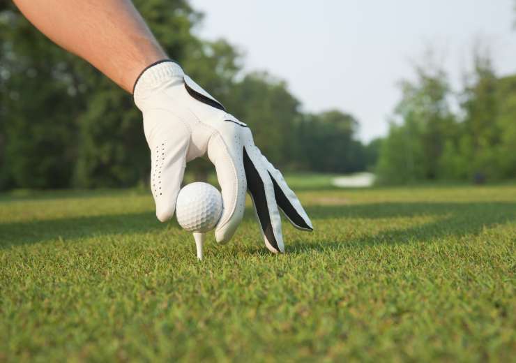 Gloved Hand of Golfer Places Ball on Tee